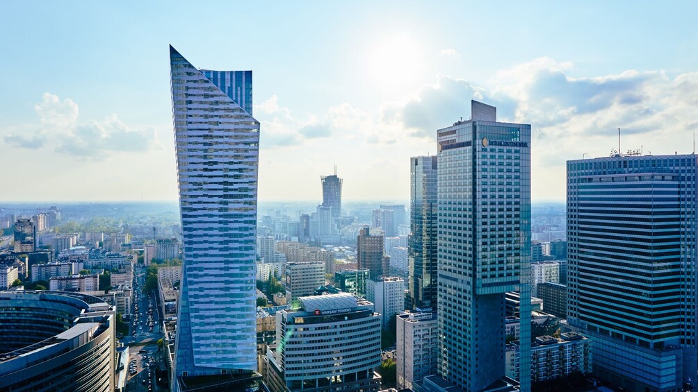 Kaupunkikuva, jossa on moderneja pilvenpiirtäjiä, mukaan lukien erottuva, kierremäinen torni ja rakennus, jonka kyltissä lukee ”Warsaw Towers”. 3