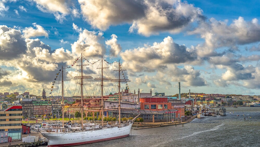 Un gran barco de vela atracado en un puerto con un paisaje urbano al fondo. 3