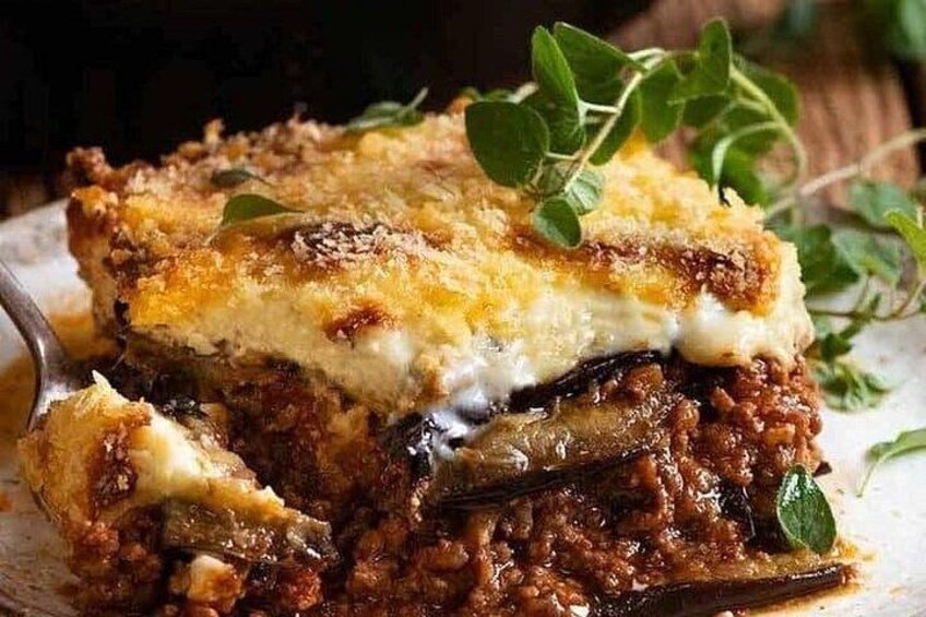 En bit lasagne med ett gyllenbrunt, smält osttäcke, garnerad med ett grönt blad. 5