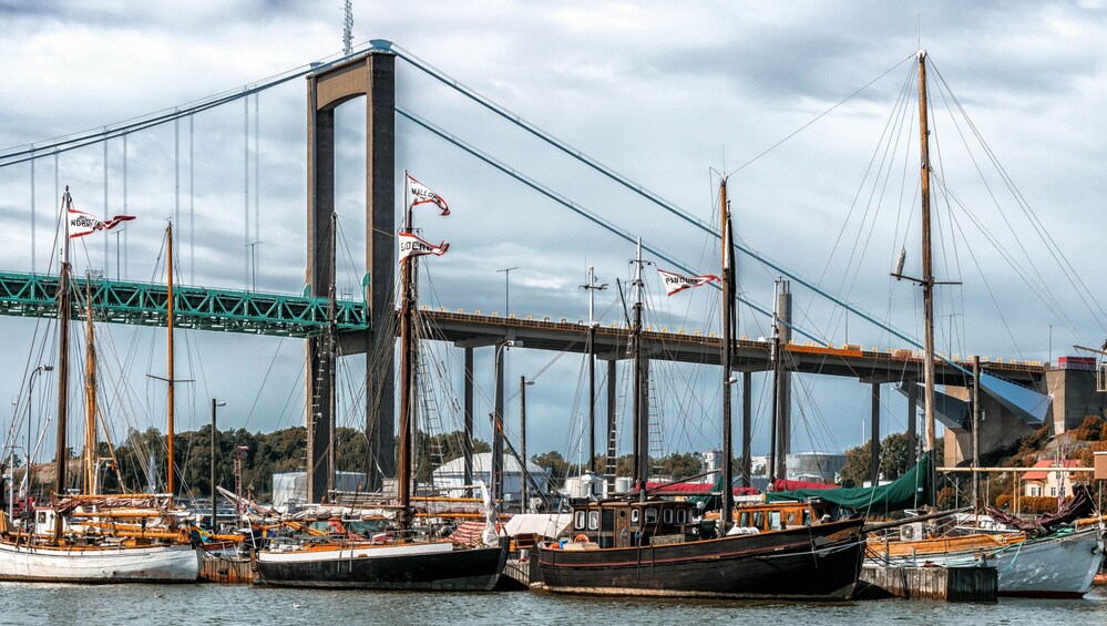 Un puente con varias banderas, un puerto con varios barcos y un paisaje urbano al fondo. 1