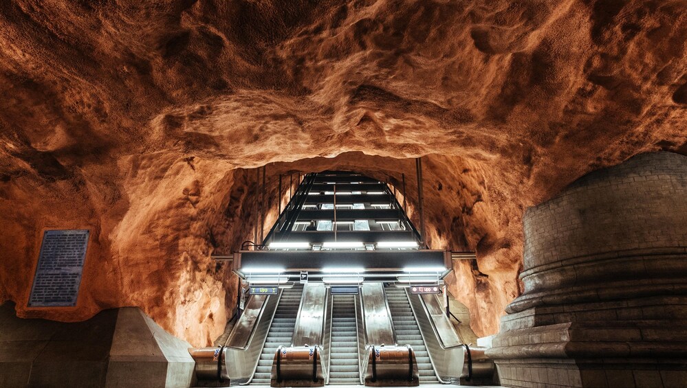 Maanalainen metroasema, jossa on liukukäytäviä ja suuri holvikaarimainen katto. 1