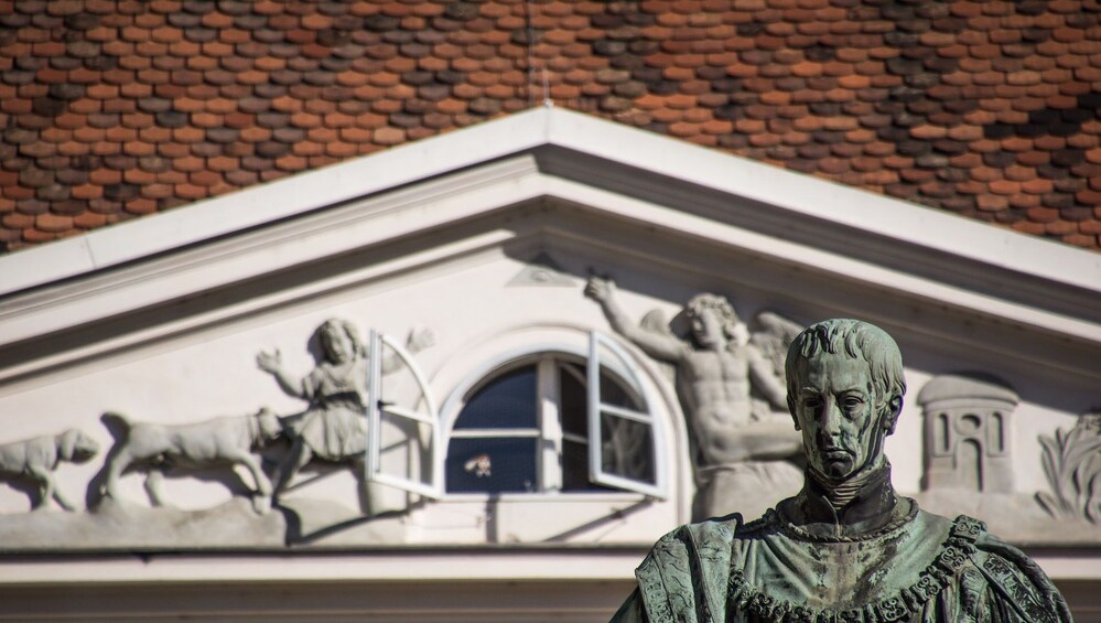 Une statue se trouve devant un bâtiment dont le toit est en briques et qui possède une fenêtre. 2