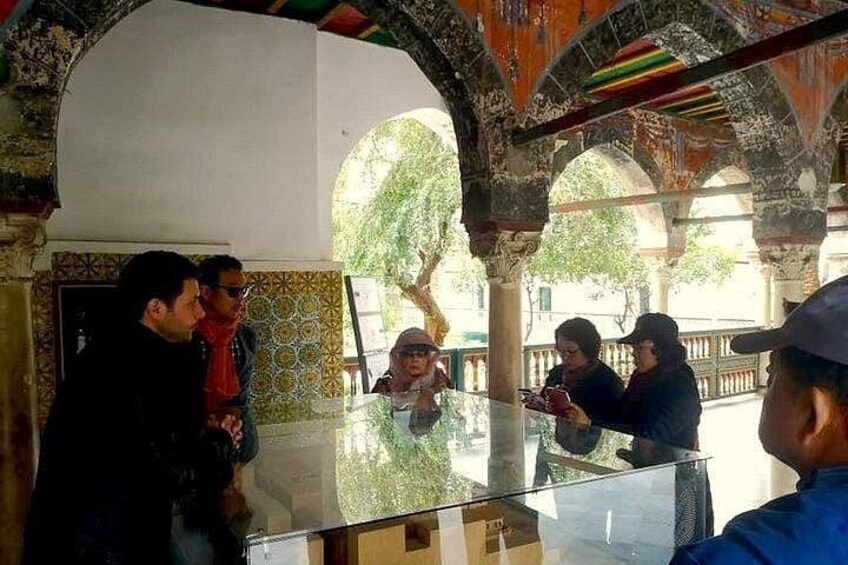Un groupe de personnes se trouve à l’intérieur d’un bâtiment doté d’arcs décoratifs et d’une cloison en verre. 2