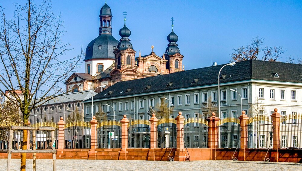 A historic building with ornate architecture and a large church with domes in the background. 3