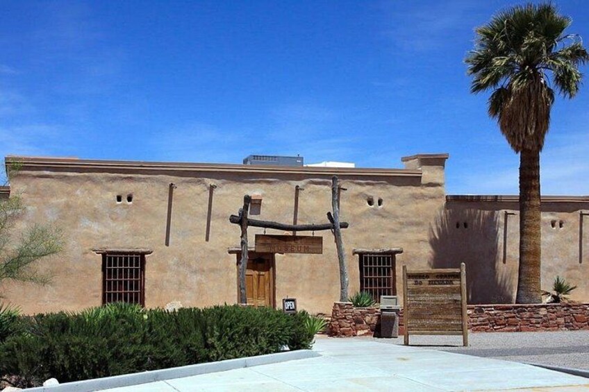 A building with a wooden door, a palm tree, and a stone wall. 5