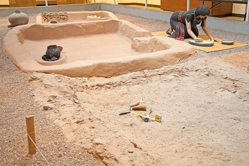 A sand model of a historical site with a person working on it. 3