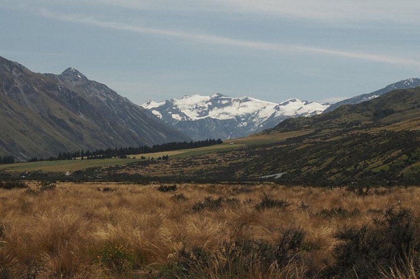 A mountainous landscape with snow-capped peaks, a grassy foreground, and a clear sky. 5