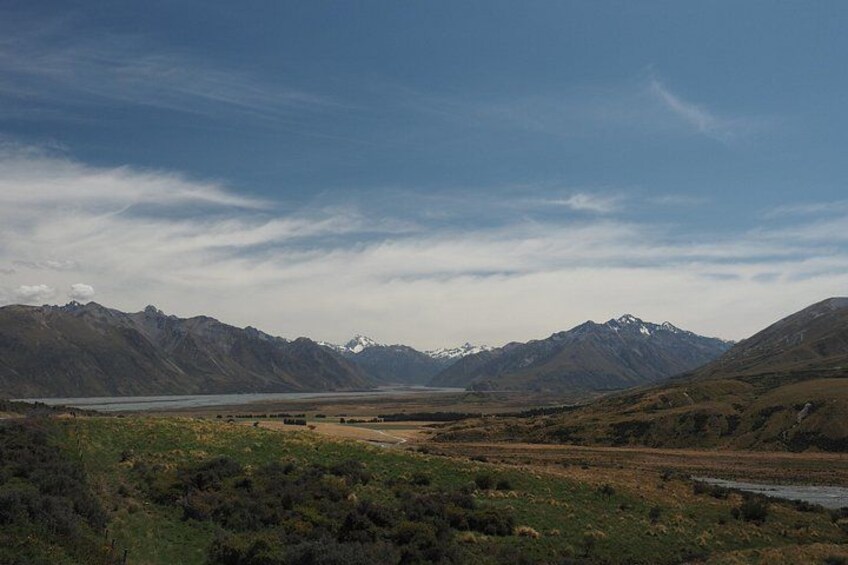 A mountainous landscape with a river, a lake, and a clear sky. 1