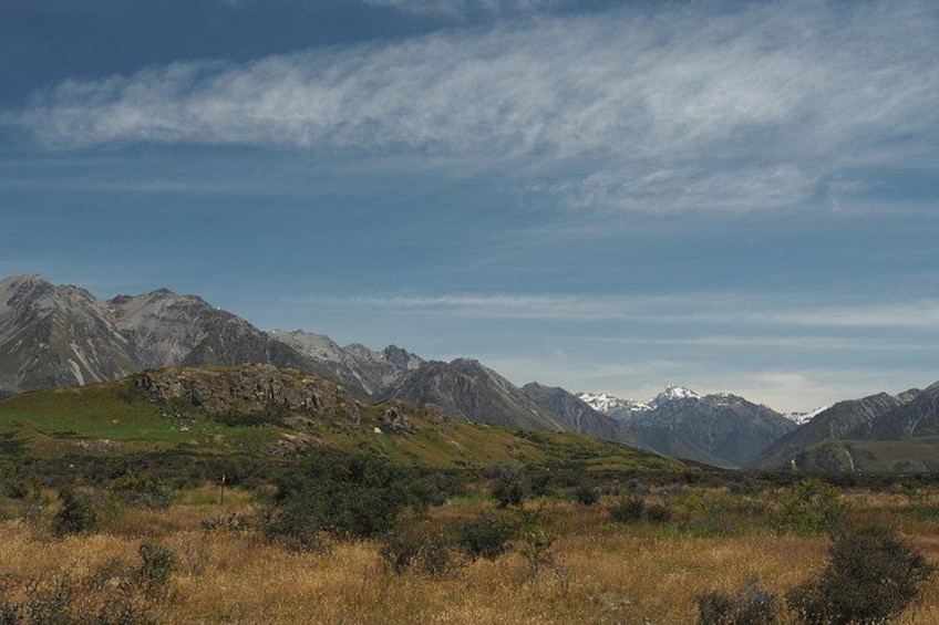 A mountainous landscape with green hills and rocky outcrops under a clear sky. 4