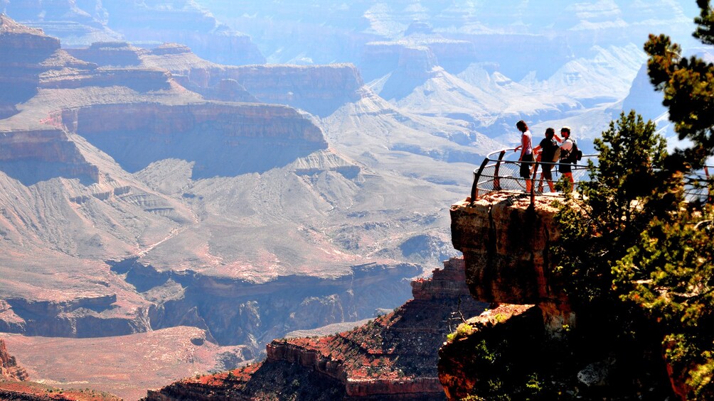 Un grupo de personas de pie en un acantilado, con vistas a un cañón. 1