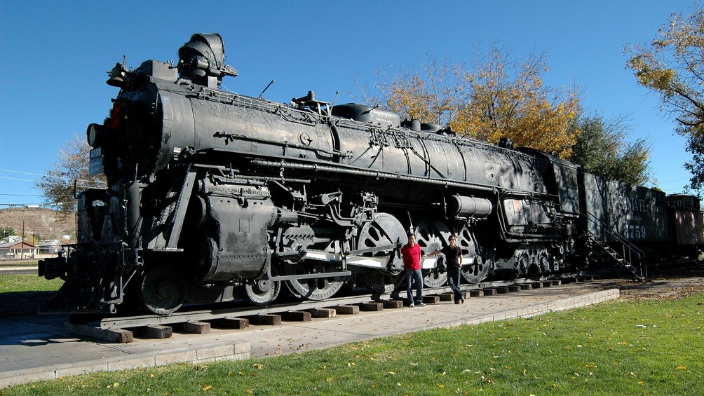 Una locomotora de vapor negra grande con los números 3759 y 3759 visibles, estacionada sobre vías con una persona de pie cerca. 3
