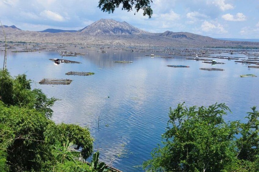 Une vaste étendue d’eau parsemée de structures flottantes, entourée de verdure et avec des montagnes en arrière-plan. 3