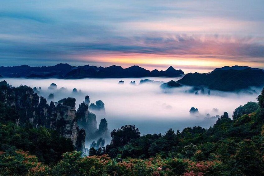 A mountainous landscape with mist-covered peaks and a sunrise or sunset sky. 3