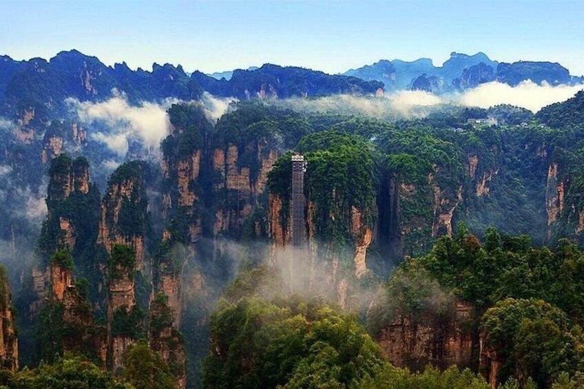 A mountainous landscape with towering rock formations and a tower structure amidst lush greenery. 5