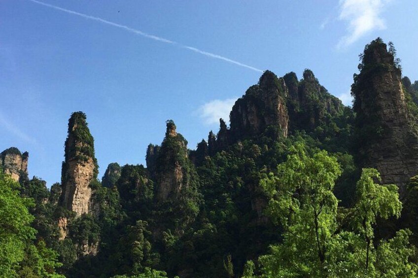 A mountainous landscape with tall rock formations and dense green foliage. 3