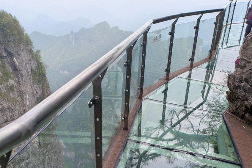 Un ponte di vetro con ringhiere metalliche, affacciato su un paesaggio montuoso. 5