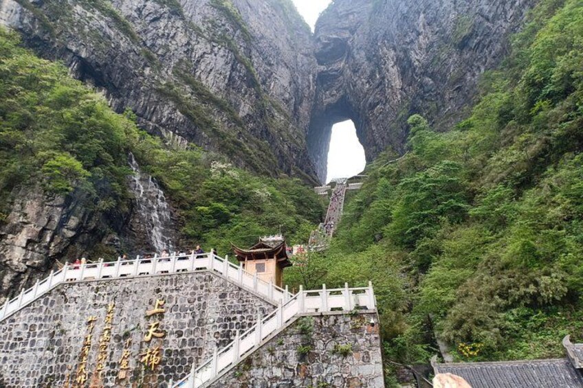 Un ponte in pietra conduce a un tempio in una zona montuosa, con l'apertura di un'ampia grotta. 3