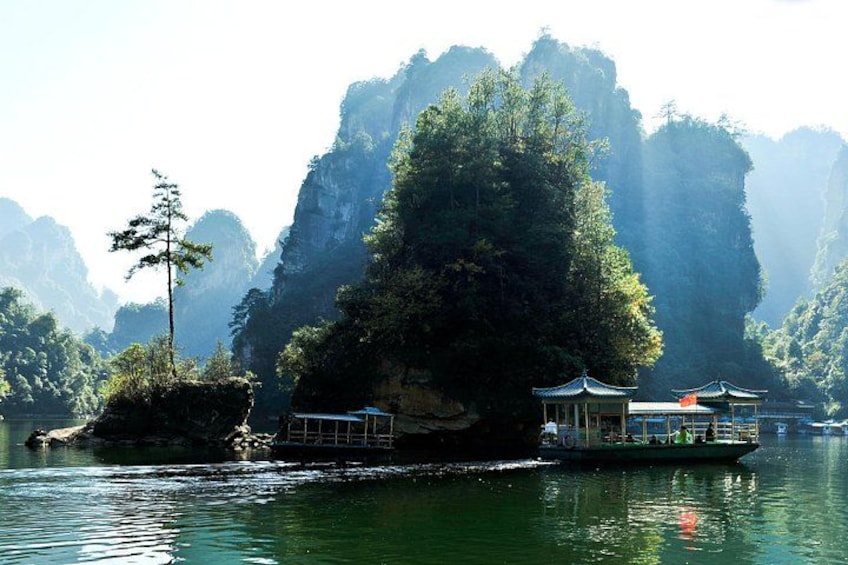 A boat with traditional architecture on a calm river surrounded by dense forest and rocky cliffs. 5