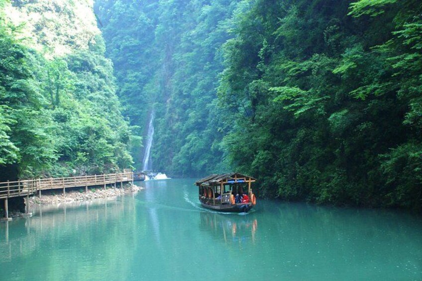 A boat on a river surrounded by lush greenery and a waterfall in the background. 3