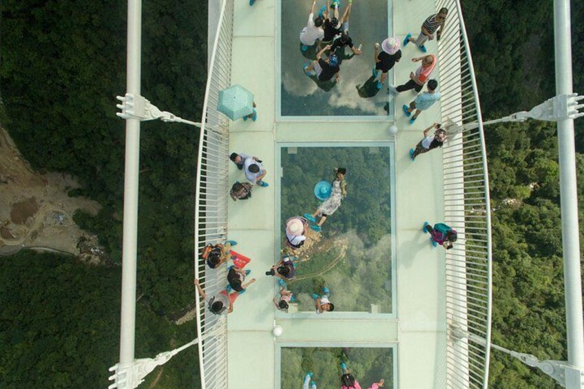 A glass-bottomed bridge with people walking on it. 2