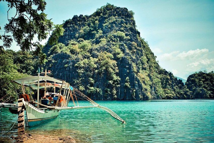 A boat anchored near a rocky island with clear turquoise water. 3