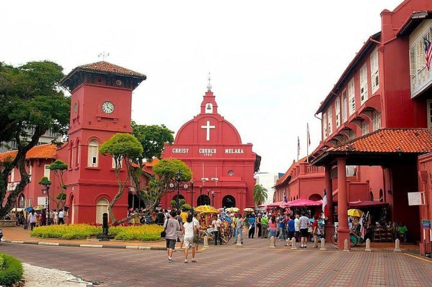 A red church with a clock tower and a dome, surrounded by pedestrians and market stalls. 5