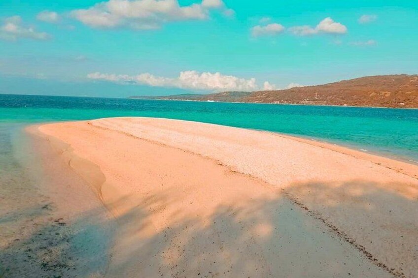 A sandy beach with clear turquoise water and distant hills. 4