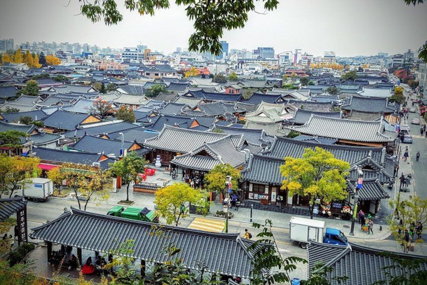 A traditional Korean village with tiled roofs, narrow streets, and a mix of residential and commercial buildings. 1
