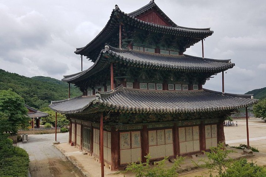 A traditional multi-tiered pagoda with a tiled roof, surrounded by greenery and a pathway. 3