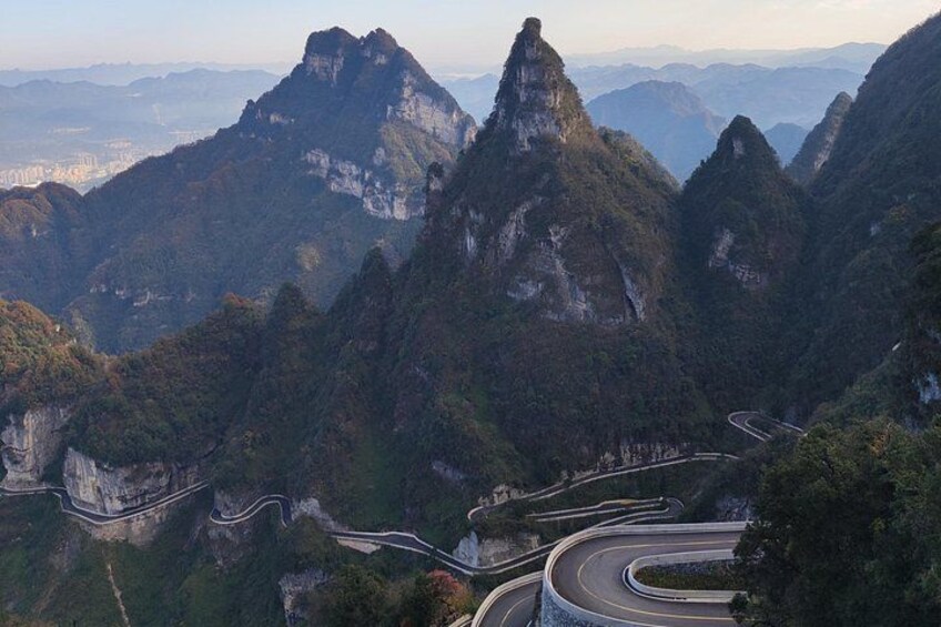 A winding mountain road surrounded by steep cliffs and dense forest. 2
