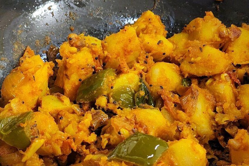 A close-up of a food dish with potatoes, green chilies, and spices. 5
