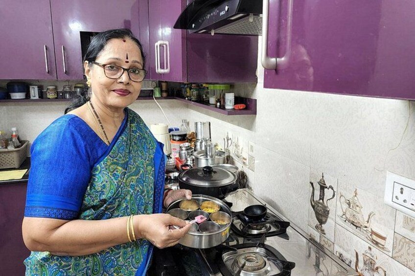 A person cooking in a kitchen with purple cabinets and decorative tiles. 3