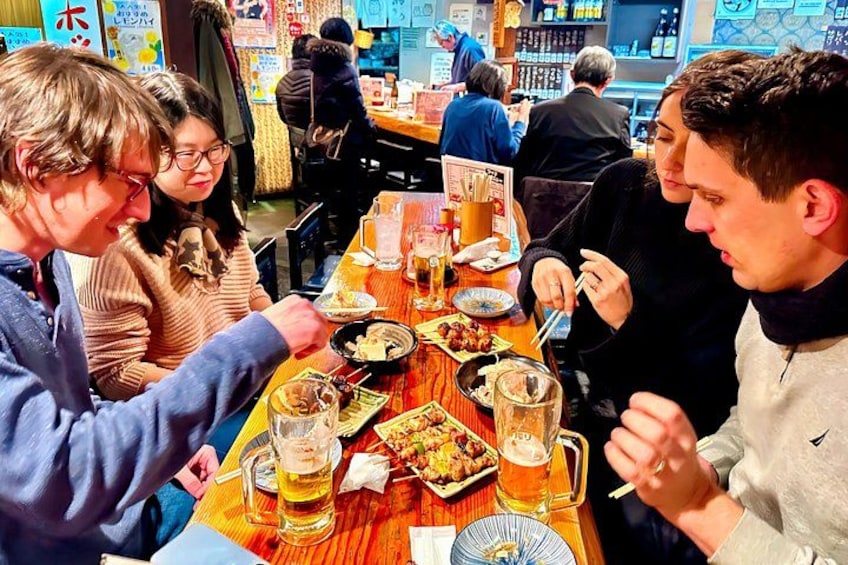Un grupo de personas cenando en un restaurante con varios platos y bebidas sobre la mesa. 1