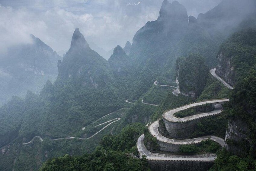 A winding mountain road surrounded by lush greenery and steep cliffs. 4