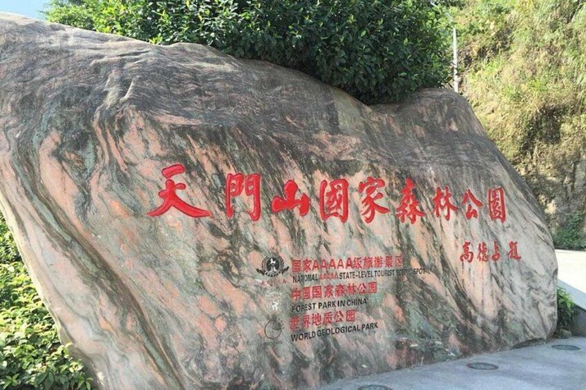 A large rock with inscriptions in Chinese characters, surrounded by greenery. 2