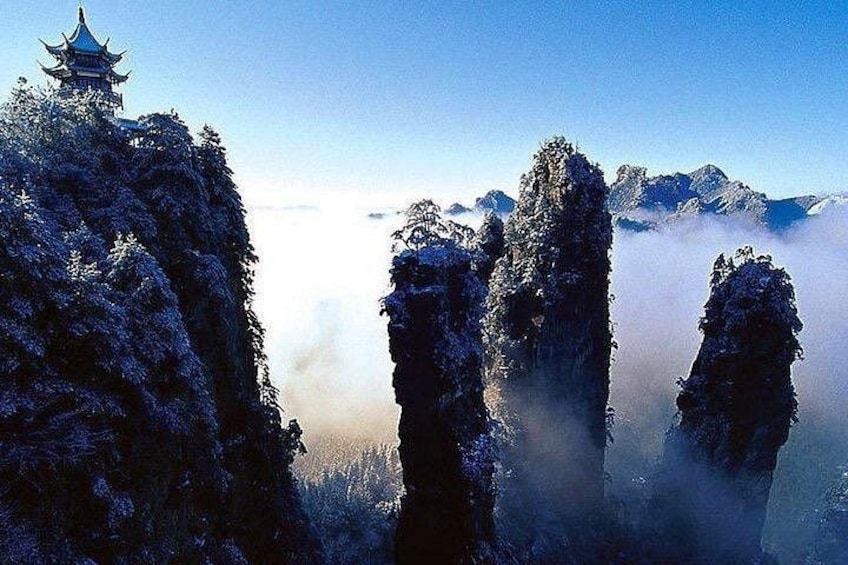 Eine traditionelle Pagode auf einem Berggipfel, umgeben von schneebedeckten Bäumen und nebelverhangenen Gipfeln. 2