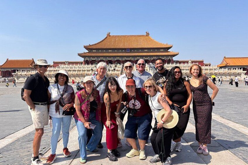 A group of people posing in front of a large, traditional building with a tiled roof. 1