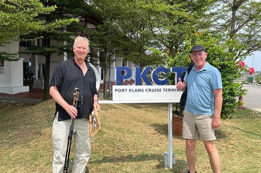 Dos hombres de pie frente a un cartel que dice 'Port Klang Cruise Terminal'. 4