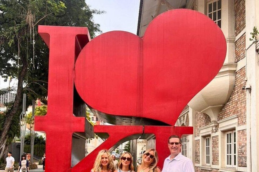 Un gran letrero rojo con la forma 'I ♥' y un recorte en forma de corazón, frente a un edificio de fachada de ladrillo. 5