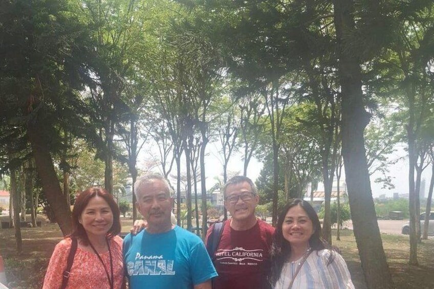 Un grupo de personas de pie bajo los árboles en un parque. 2