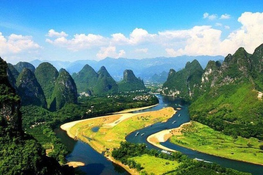 A river winding through a mountainous landscape with lush greenery and distant mountains under a clear sky. 4