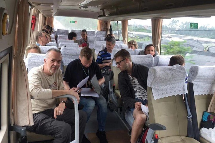 A bus interior with passengers seated, some using laptops, and a view of a highway outside. 5