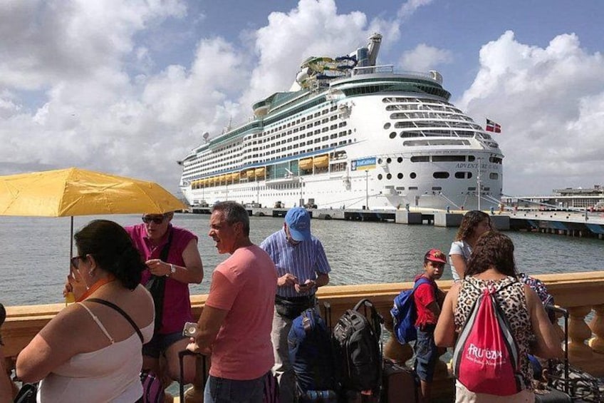 A cruise ship docked at a port with people standing on the dock. 1