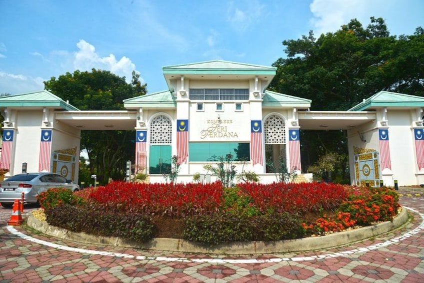 A building with a green roof and white walls, surrounded by a flower bed with red flowers. 2