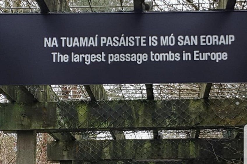 A sign with text in two languages, a metal fence, and a metal structure. 4