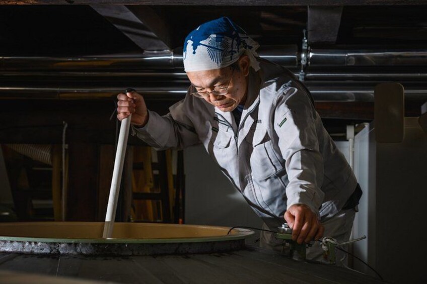 A person working with a large circular machine, possibly in a workshop or industrial setting. 3