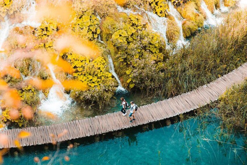 A wooden bridge over a body of water with people walking on it. 2