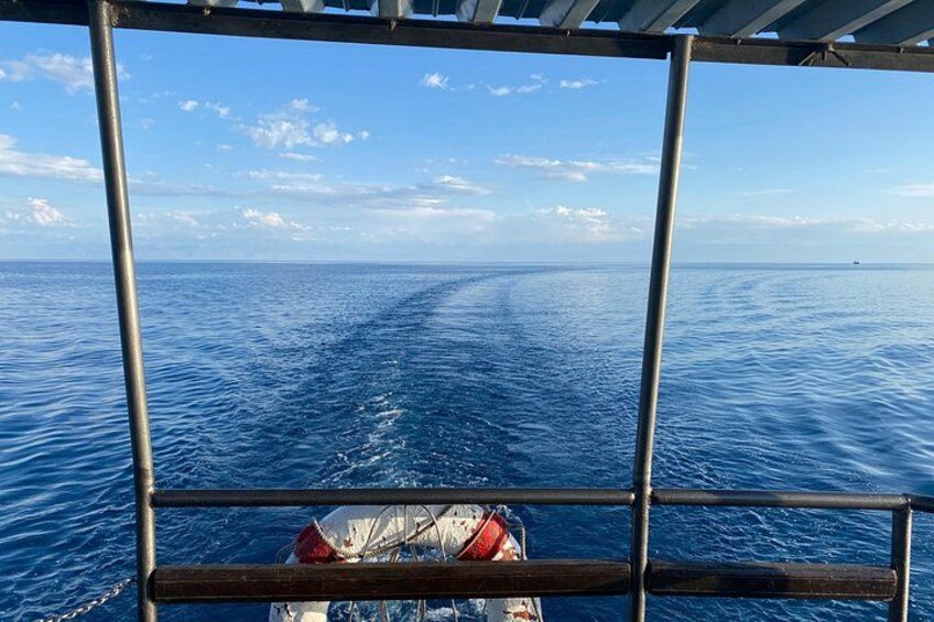 A boat's wake in the ocean, a clear sky, and a distant horizon. 2