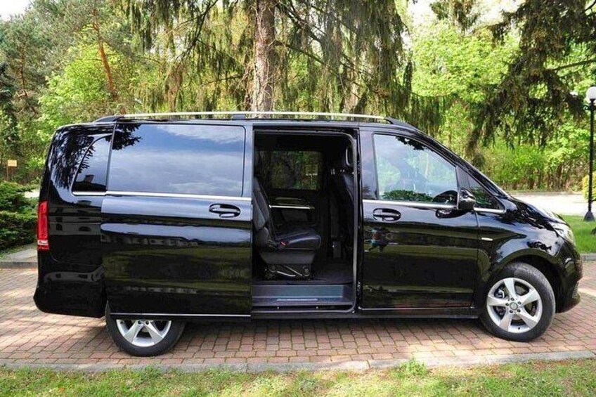A black van parked on a brick path in a park with trees in the background. 2