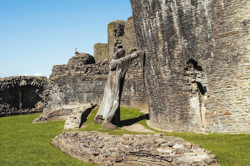 Una estructura de piedra histórica con una estatua de una persona vestida con ropas amplias. 3